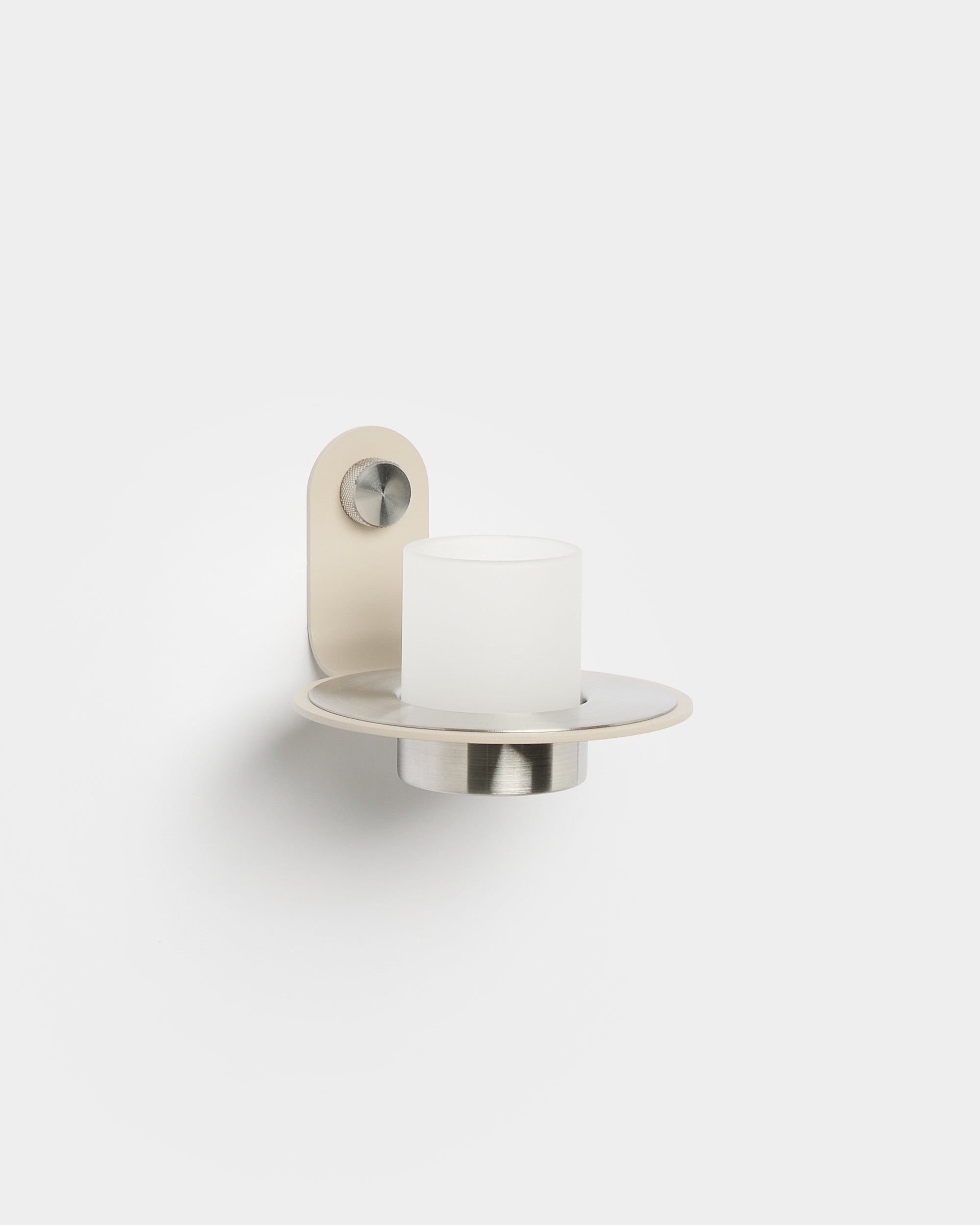 De Norr Candle Holder van WoodUpp, met een basis van beige roestvrij steel, geplaatst op een Akupanel Akoestisch paneel voor een modern Scandinavisch accent.